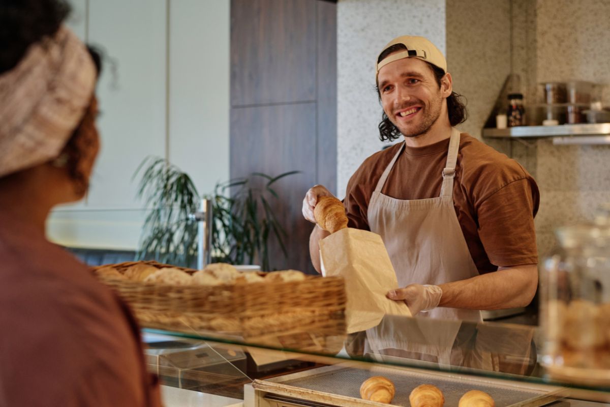 Bakery worker interacting with a customer, showing how POS systems free up time for better service.