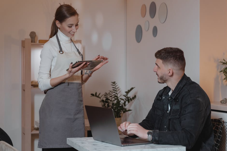 Waitress entering an order on a tablet system while speaking with a customer at a restaurant table